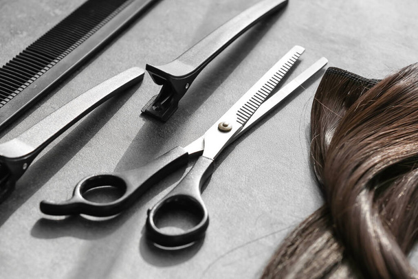 Barber set with strand of brunette hair on grunge background, closeup - Photo, Image