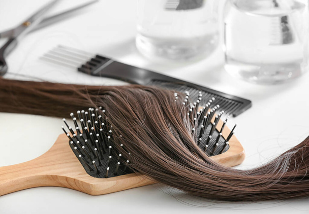 Brush with strand of brunette hair on table, closeup - Photo, Image