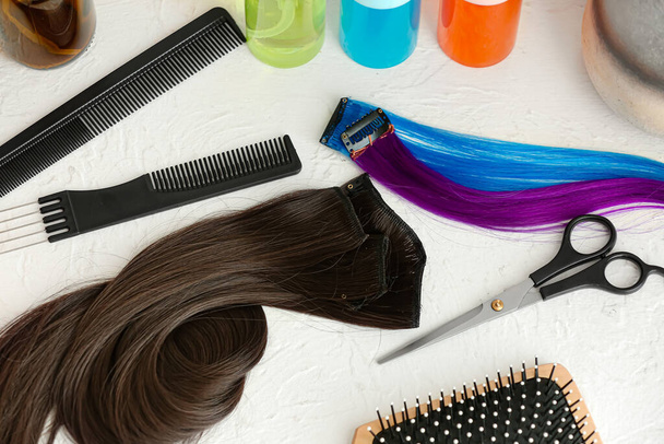 Парикмахерские инструменты и пряди красивых волос на белом фоне - Фото, изображение