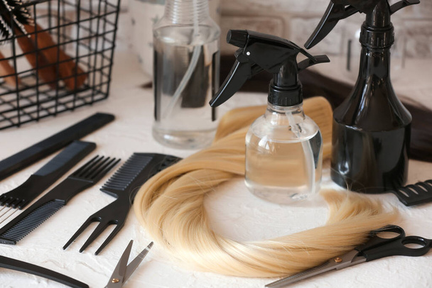 Парикмахерские инструменты и прядь светлых волос на столе в салоне красоты - Фото, изображение