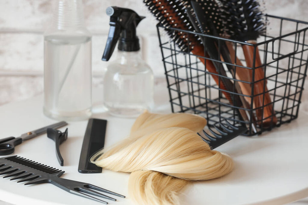 Borbély szerszámok és szál szőke haj az asztalon a szépségszalonban - Fotó, kép