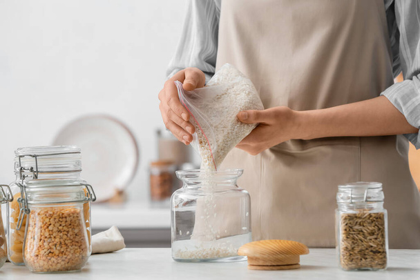 Woman pouring rice into jar in kitchen - Photo, Image