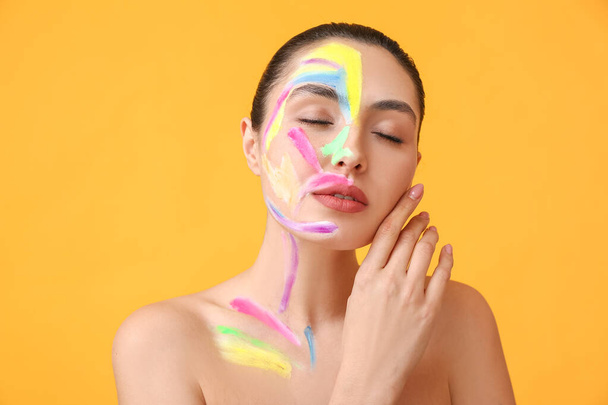 Beautiful young woman with paint on her body against color background - Photo, Image
