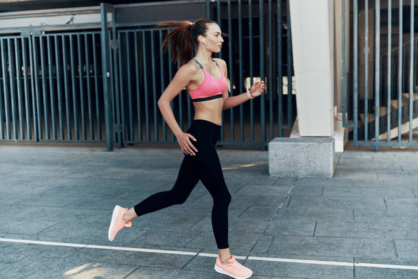 Full length of beautiful young woman in sports clothing running outdoors - Foto, immagini