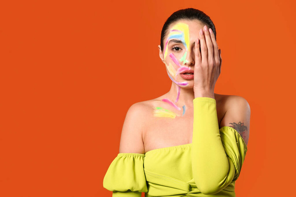 Beautiful young woman with paint on her body against color background - Photo, Image