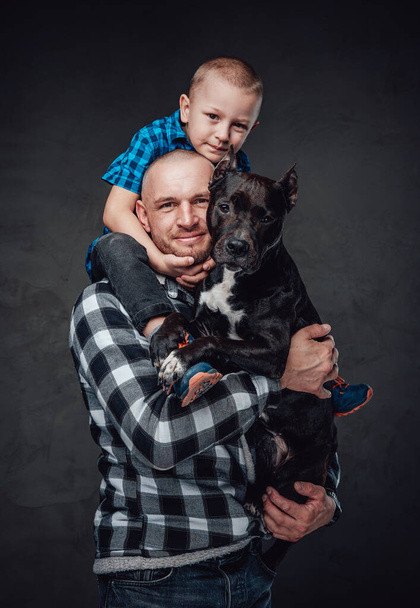 Adult father hugging his son and dark brown dog - Foto, afbeelding