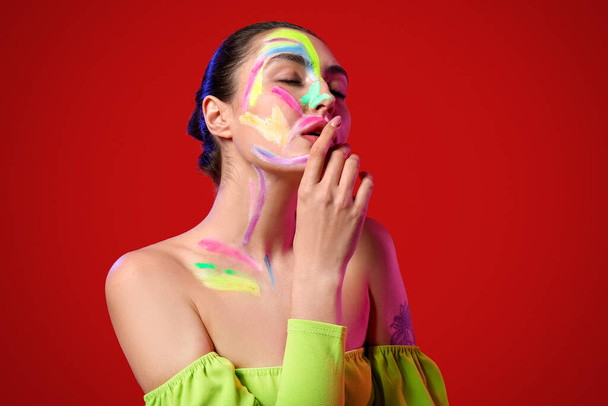 Gyönyörű fiatal nő festékkel a testén szemben színes háttér - Fotó, kép