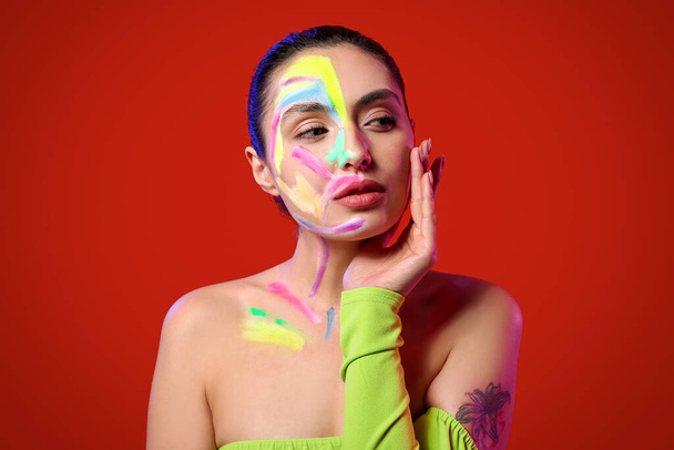 Beautiful young woman with paint on her body against color background - Fotografie, Obrázek