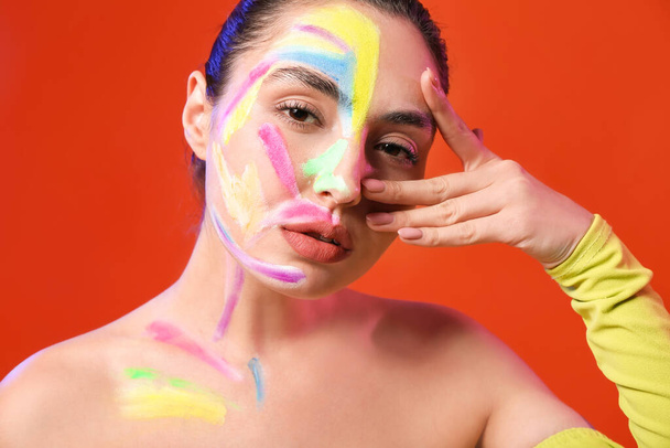 Beautiful young woman with paint on her body against color background - Valokuva, kuva