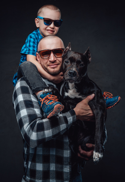 Lachende vader knuffelende hond en zijn kleine zoon - Foto, afbeelding