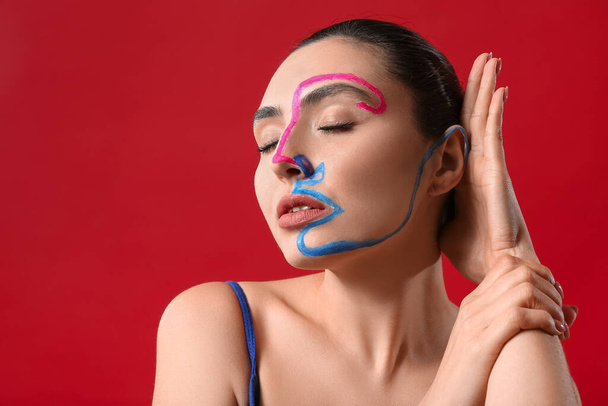 Beautiful young woman with paint on her face against color background - Фото, зображення
