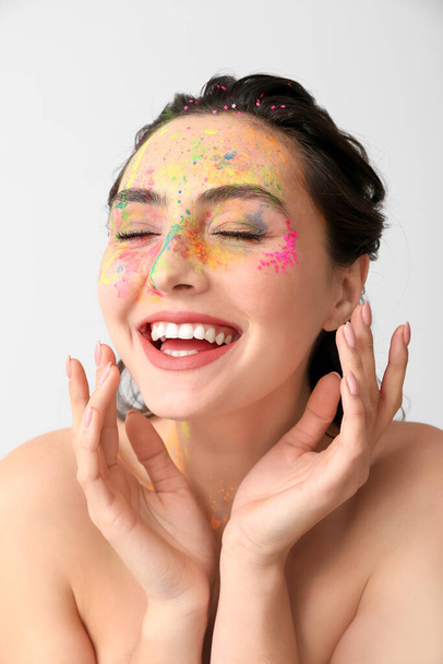 Beautiful young woman with paint on her face against light background - Foto, immagini
