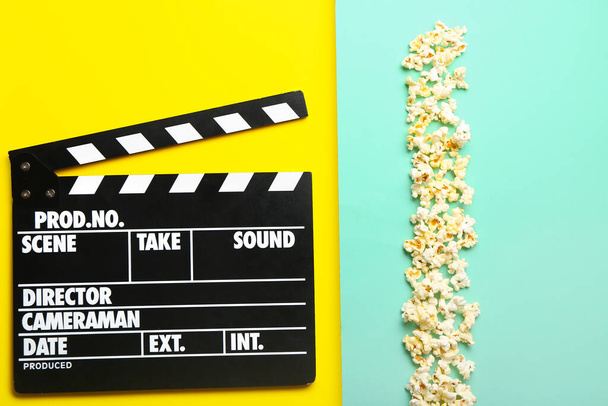 Klaszczący film i popcorn na kolorowym tle - Zdjęcie, obraz
