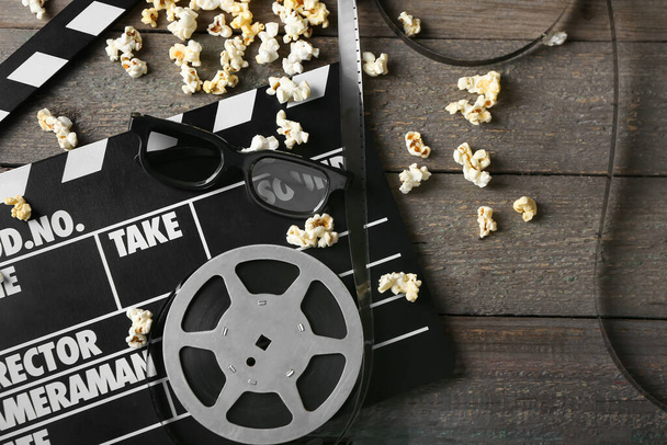 Kompozice s popcornem, 3D brýlemi a filmovým tlesknutím na tmavém dřevěném pozadí - Fotografie, Obrázek