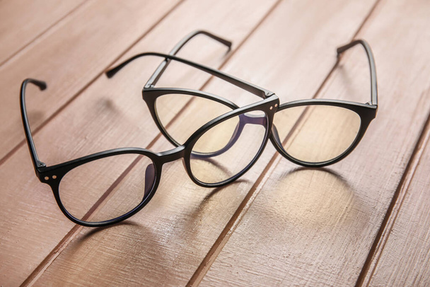 Different stylish eyeglasses on color wooden background, closeup - Fotó, kép