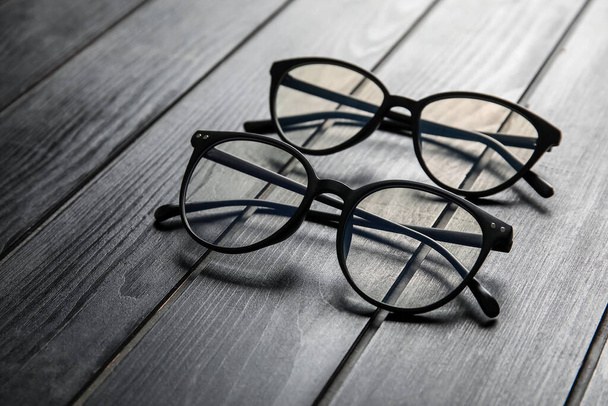 Different stylish eyeglasses on grey wooden background, closeup - Photo, Image