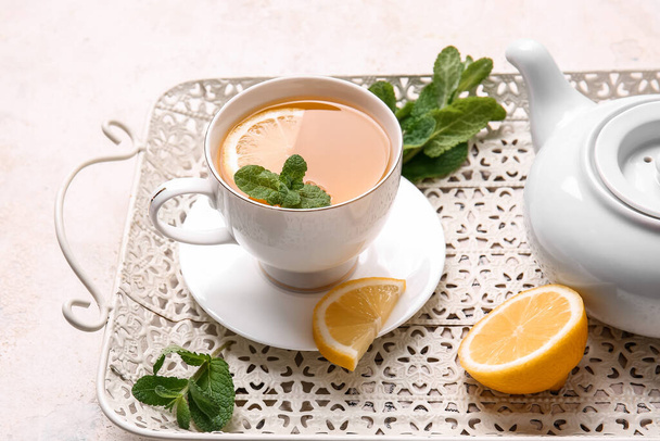 Tray with cup of tasty green tea, pot and ingredients on grunge background - Photo, Image