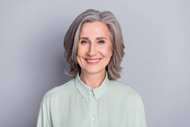 Photo of happy cheerful smiling beautiful mature woman wearing green shirt isolated on grey color background - Fotó, kép