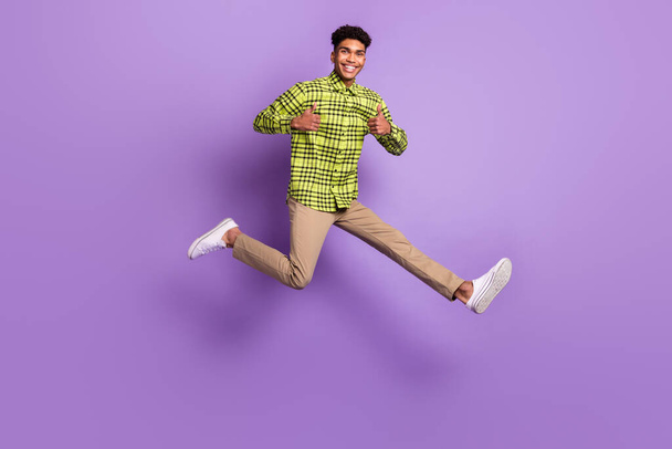Full size photo of brunette dark skin man jump up show thumbs up wear casual clothes isolated on violet color background - Foto, Imagem