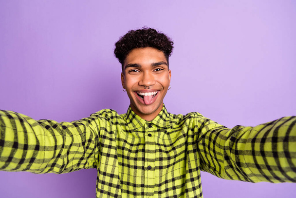 Photo of attractive funny young dark skin man tongue out make selfie camera isolated on violet color background - Fotografie, Obrázek