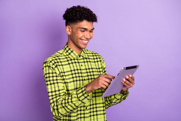 Photo of charming positive afro american man look read tablet good mood smile isolated on purple color background - Foto, afbeelding