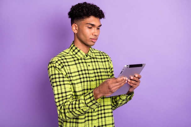 Portrait of handsome focused brunet guy holding in hands using device reading isolated over violet purple color background - Fotó, kép