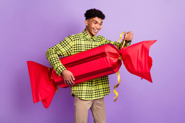 Photo portrait of guy cheerful unpacking big present sweet dessert smiling guess what inside isolated on pastel purple color background - Foto, afbeelding