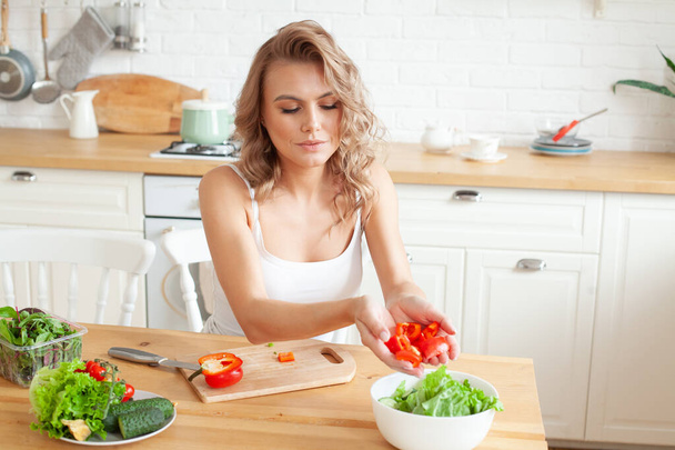 Boldog fiatal nő salátát készít a konyhában. - Fotó, kép