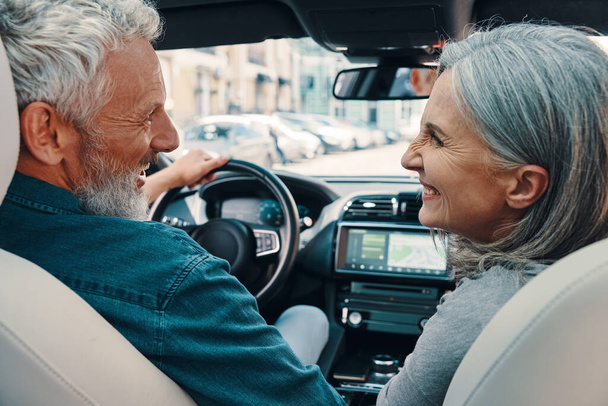 Rear view of active senior couple enjoying car ride while sitting on front seats of the car - Foto, Bild