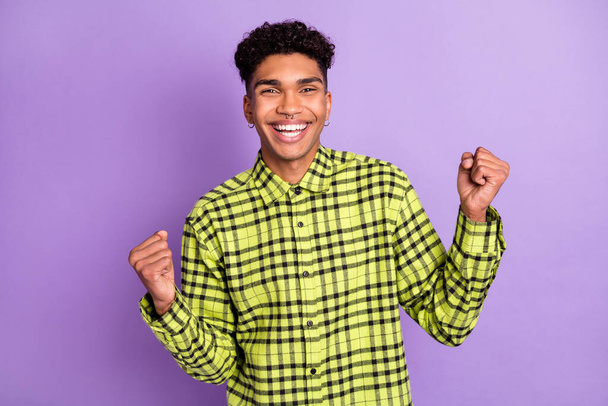 Portrait of attractive cheerful guy wear checked shirt rejoicing good luck isolated over violet purple color background - Fotó, kép