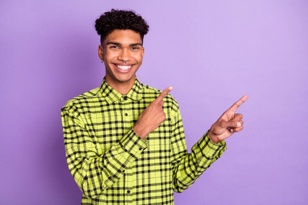 Portrait of attractive cheerful guy wear checked shirt demonstrating copy space isolated over violet purple color background - Foto, imagen