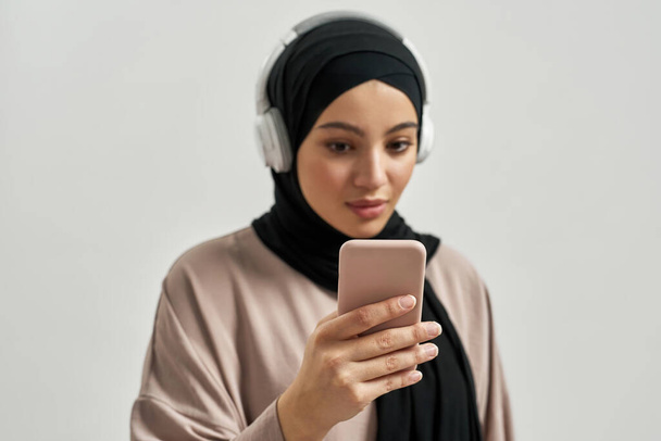 Cute young arabian woman in hijab and headphones - Photo, Image