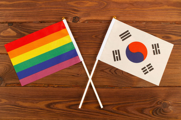 Tęczowa flaga LGBT i flaga Korei Południowej na brązowym tle desek drewnianych. Miesiąc Pychy LGBT. LGBTQ. LGBTQIA. Zamknij się. Widok z góry - Zdjęcie, obraz