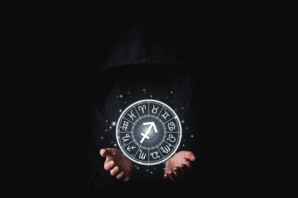 Women's hand in the dark holding glowing astrological signs of the zodiac in a circle. - Photo, Image
