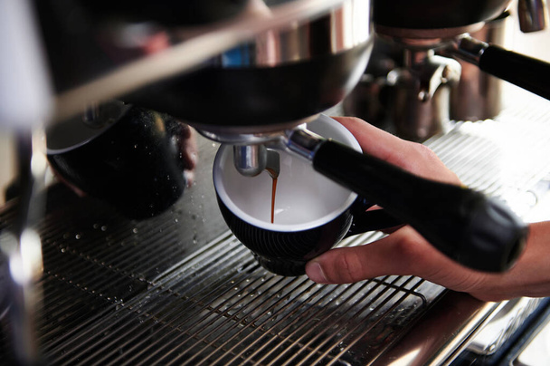 Primer plano del espresso que vierte de la máquina de café en tazas. Cervecería de café profesional. - Foto, imagen