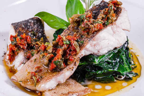 Pesce bianco in salsa cremosa con spinaci su un piatto bianco - Foto, immagini
