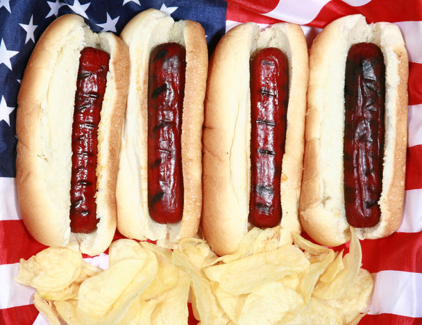 Χοτ Ντογκ. Σαρακοστή Ιουλίου Χοτ Ντογκ. Μπάρμπεκιου Κόμμα Τροφίμων. Αμερικάνικο πατριωτικό χοτ ντογκ με αμερικάνικη σημαία. Γιορτάζοντας την Ημέρα Ανεξαρτησίας στις 4 Ιουλίου στις Ηνωμένες Πολιτείες της Αμερικής. Μέρα Ανεξαρτησίας χοτ ντογκ. Hot Dogs το τέλειο φαγητό για διακοπές και πάρτι. - Φωτογραφία, εικόνα