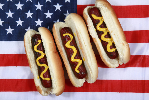 Hot Dog. Forth of July Hot Dog. Comida para churrascos. Cachorro quente patriótico americano com bandeira dos EUA. Celebrando o Dia da Independência no dia 4 de julho nos Estados Unidos da América. Dia da independência cachorro-quente. Três cachorros quentes com mostarda em uma bandeira americana. Delicioso. - Foto, Imagem