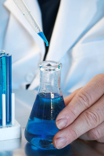 Χημεία. Διαφανής γυάλινη φιάλη και ποτήρι ζέσεως με διάλυμα Blue στη χημεία. Εργαστήριο Επιστημονικής Έρευνας. Επιστήμονας που εργάζεται σε μια θεραπεία για Coronavirus. Ερευνητικό εργαστήριο Covid-19 που εργάζεται σε μια θεραπεία για την πανδημία. Εργαστήριο Ιατρικής Έρευνας. Covid-19 Έρευνα θεραπείας. - Φωτογραφία, εικόνα
