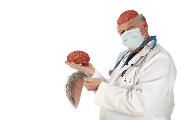 Εγκεφαλοχειρουργός Ιατρική και επιστήμη. ένας γιατρός ή ένας νευροχειρουργός κρατάει έναν εγκέφαλο με ένα περίεργο μπερδεμένο βλέμμα στο πρόσωπό του. απομονωμένο σε λευκό. Υπάρχει χώρος για το μήνυμά σου. ανθρώπινος εγκέφαλος απομονωμένος στο λευκό. Ένας νευροχειρουργός αντικαθιστά τον παλιό του εγκέφαλο με έναν καινούριο..  - Φωτογραφία, εικόνα