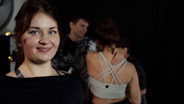 Una chica habla sonriendo en cámara mientras sus amigos hablan a sus espaldas - Foto, imagen
