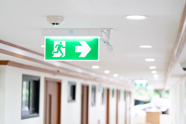 Een pijl lichtbak teken van noodhulp VUUR UIT wordt opgehangen aan het plafond in het ziekenhuis loopbrug, Idee voor brand of evacuatie boren. - Foto, afbeelding