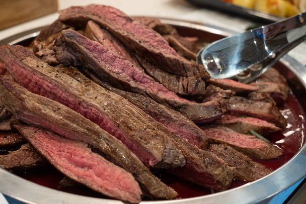 Яловичий стейк зварений середній рідкісний і нарізаний скибочками. Кров'яне червоне м'ясо подається на підносі. Приготування м'яса
. - Фото, зображення