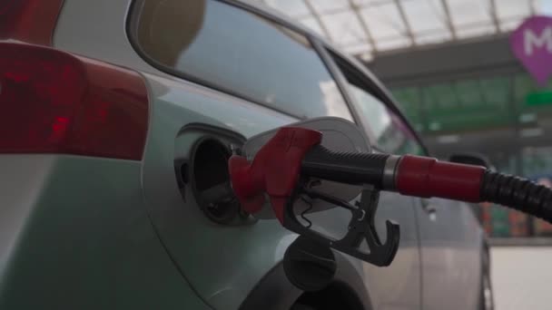 Refueling modern car at gas filling station close up. Filling car petrol. Pump gas fuel at gasoline oil station for nozzle tank. Handle of refueling gun. Insert red gun into tank of car for refueling - Filmati, video