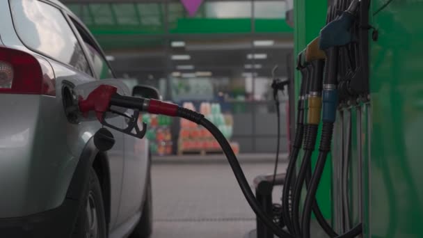 Refueling modern car at gas filling station close up. Filling car petrol. Pump gas fuel at gasoline oil station for nozzle tank. Handle of refueling gun. Insert red gun into tank of car for refueling - Footage, Video