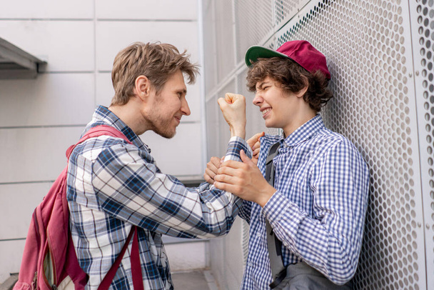 two guys fight each other, one adult threaten to the student, push against the wall, bully concepts - Photo, Image