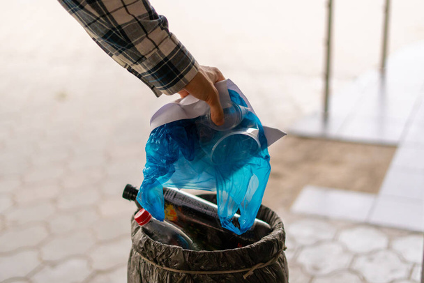tirando papel y basura plástica en una urna de basura en las calles de la ciudad - Foto, Imagen