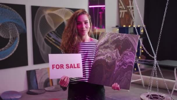 Genç bir kadın satılık bir resim gösteriyor.  - Video, Çekim