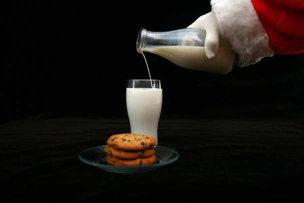 Joulupukki nauttii maidosta ja kekseistä. Maitoa ja keksejä joulupukille. Joulupukki syö maitoa ja keksejä. Keksejä joulupukille. Tuoreita keksejä ja kaakaota vaahtokarkeilla, jotka on jätetty joulupukin pöydälle. Lahja joulupukille jouluaattona. - Valokuva, kuva