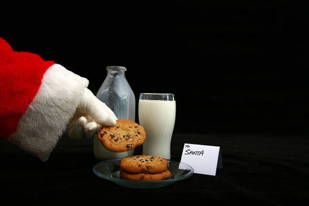 Le Père Noël aime le lait et les biscuits. Du lait et des biscuits pour le Père Noël. Le Père Noël mange du lait et des biscuits. Cookies pour le Père Noël. Biscuits au four frais et chocolat chaud avec guimauves laissés sur une table pour le Père Noël. Un cadeau pour le Père Noël la veille de Noël. - Photo, image